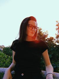 Low section of woman standing against plants against clear sky