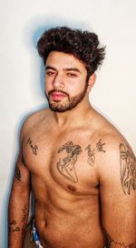 Portrait of shirtless young man standing against white background