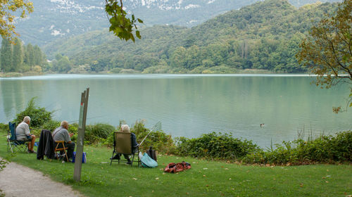 People fishing in lake against mountains