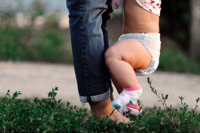 Low section of mother and baby by lake