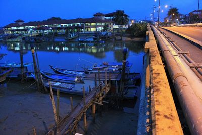 Boats moored at illuminated shore against sky