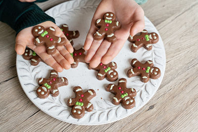 Cropped image of boy holding gingerbread cookies at home