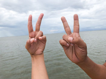 Midsection of person hand in sea against sky