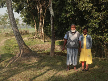 Elderly man and young girl standing on field.