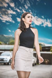 Beautiful young woman standing against sky