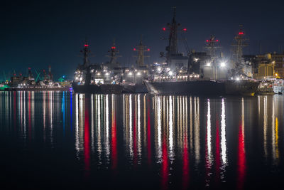 Illuminated boats in sea against clear sky at night