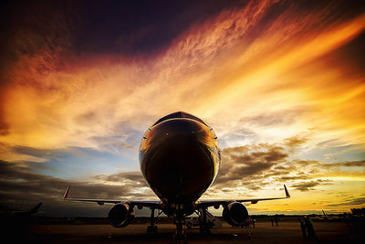 Airplane on airport runway against sky during sunset