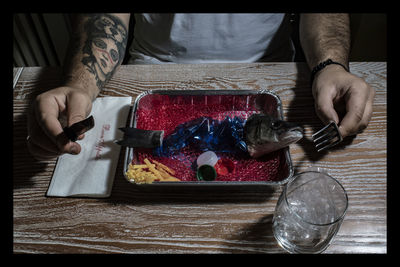 Close-up of hand holding cigarette on table