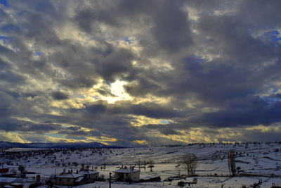 Snow covered landscape against cloudy sky