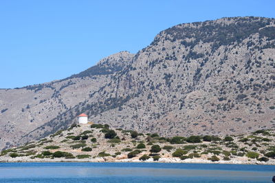 Scenic view of sea and mountain against clear blue sky