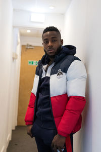 Portrait of young man standing against wall
