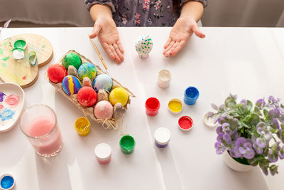 The hands of a little girl, palms up, demonstrate a coloring egg, on a white table
