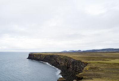 Man in yellow jacket overlooking the krísuvíkurberg cliffs in iceland