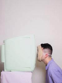 Side view of young man against white wall