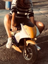 Low section of woman sitting on toy motorcycle