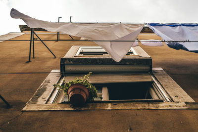 Low angle view of clothes drying on building against sky