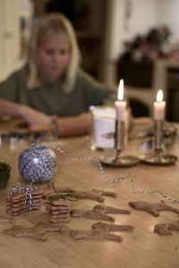 Midsection of woman with candles on table at home