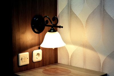 Electric lamp on table against wall at home