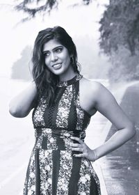 Portrait of smiling young woman standing against trees