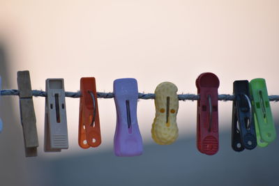 Close-up of clothespins hanging on clothesline against white background