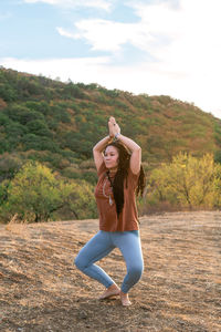 Portrait of beautiful european. woman is doing yoga exercise outside on background of mountains.
