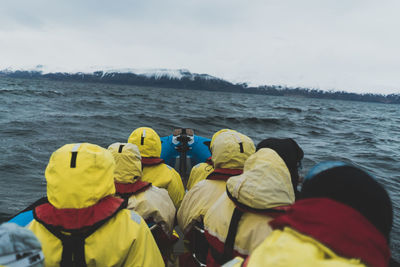 Rear view of people in boat on sea against sky