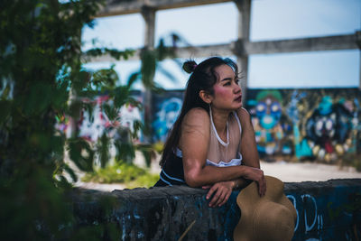 Side view of young woman sitting outdoors