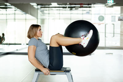 A young woman does abs exercises in the gym on a bench using a fitball. the concept of sports 