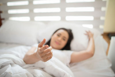 Woman gesturing while lying on bed at home