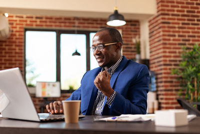 Portrait of businessman using laptop at office