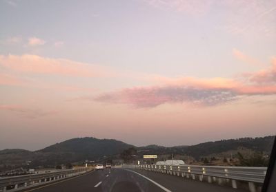Road in city against sky during sunset