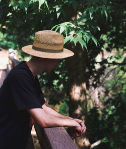 Side view of young man standing by railing while looking down