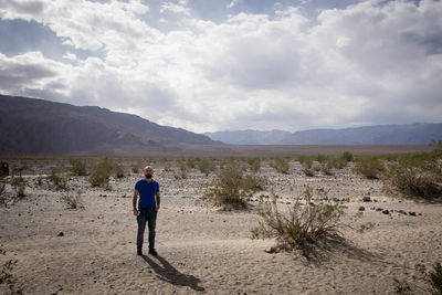 Rear view of man walking on desert against sky