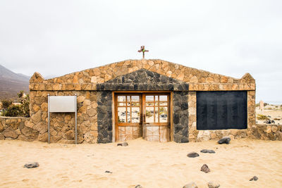 Abandoned house on desert against sky