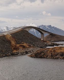 Bridge over river against cloudy sky