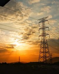 Low angle view of silhouette electricity pylon against sky during sunset