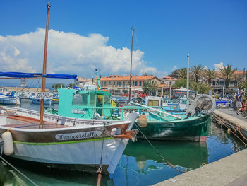 Boats moored at harbor against blue sky