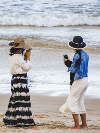 Rear view of friends standing at beach