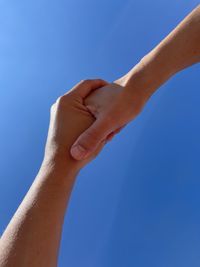 Close up of holding hands against blue background