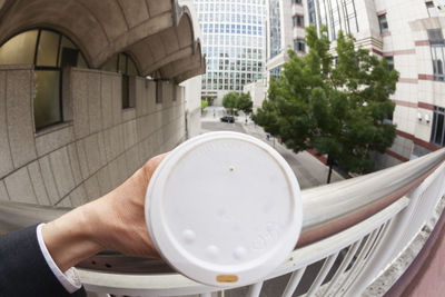 Close-up of businessman holding disposable cup in city