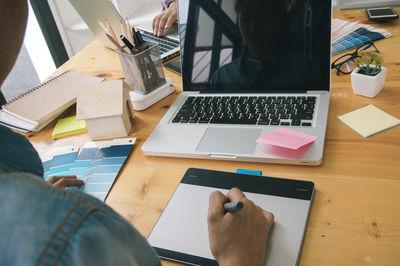 Midsection of businessman using laptop at desk in office