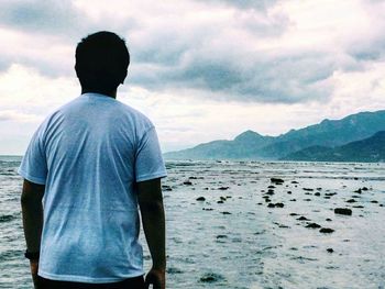 Rear view of man on beach against sky