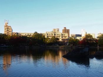 Buildings by river against clear sky