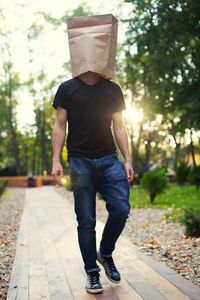 Man wearing paper on head while walking on footpath