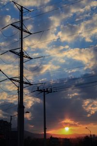 Low angle view of electricity pylon against sky during sunset