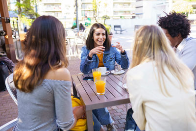 Young woman standing against people at outdoor cafe