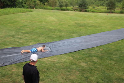 Rear view of man climbing on grass in park