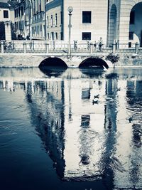 Arch bridge over river against buildings in city