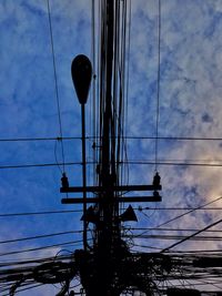 Low angle view of electricity pylon against cloudy sky