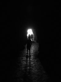 Silhouette woman walking on illuminated road at night